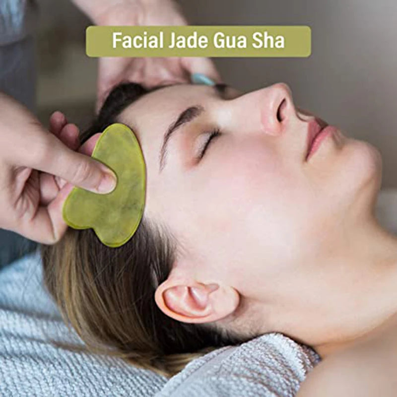 Plaque de gua sha et rouleau de jade en pierre verte posés sur un linge de coton